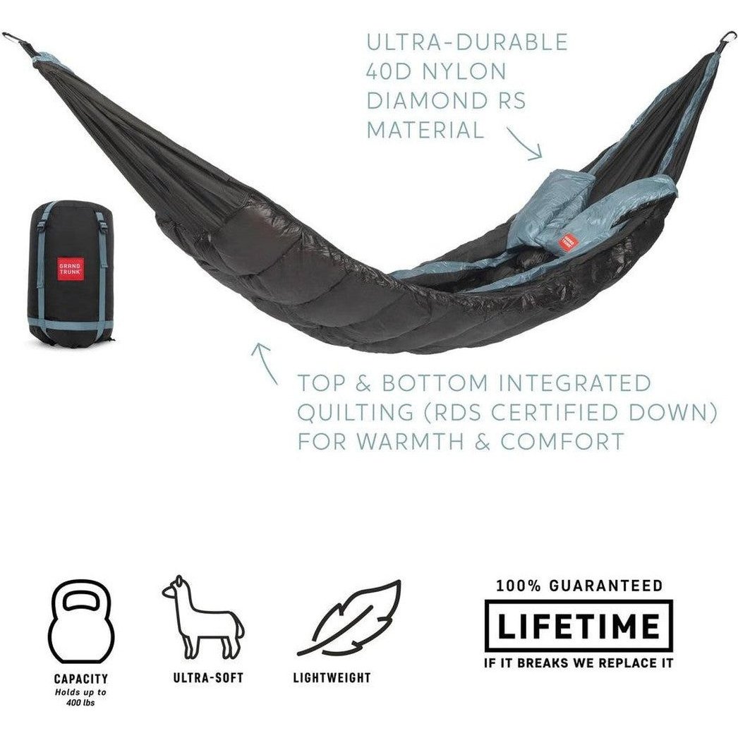 A charcoal Grand Trunk Evolution Down Hammock laid out with its compact bag visible, showing top and bottom quilting for warmth.
