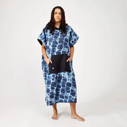 A model wearing the Nomadix Changing Poncho in Agua Blue stands against a plain white background.