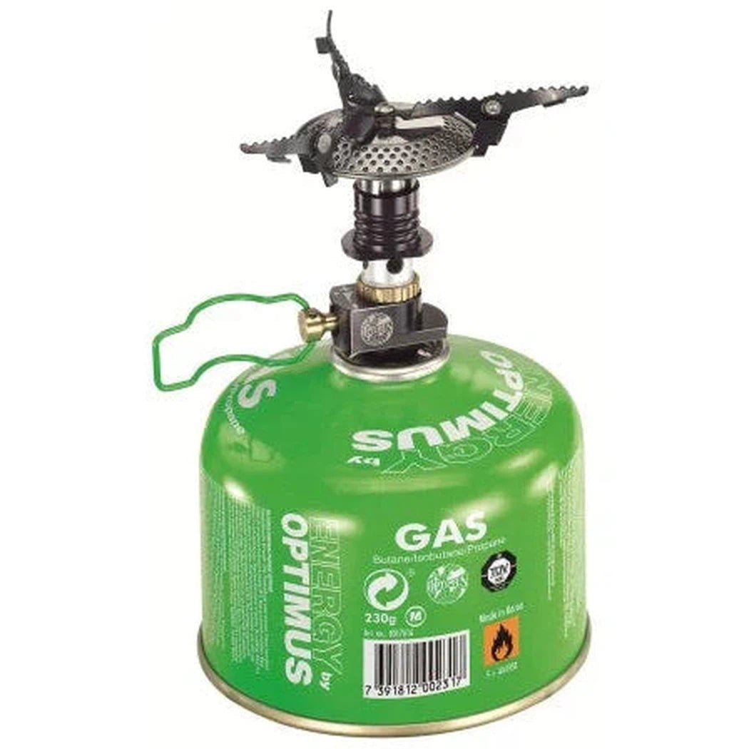 A green Optimus Crux camping stove with a black burner on top, shown from a front angle against a white background.
