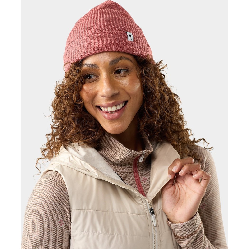 Model wearing the Smartwool Beanie in Rosewood Heather with curly hair and a beige vest.