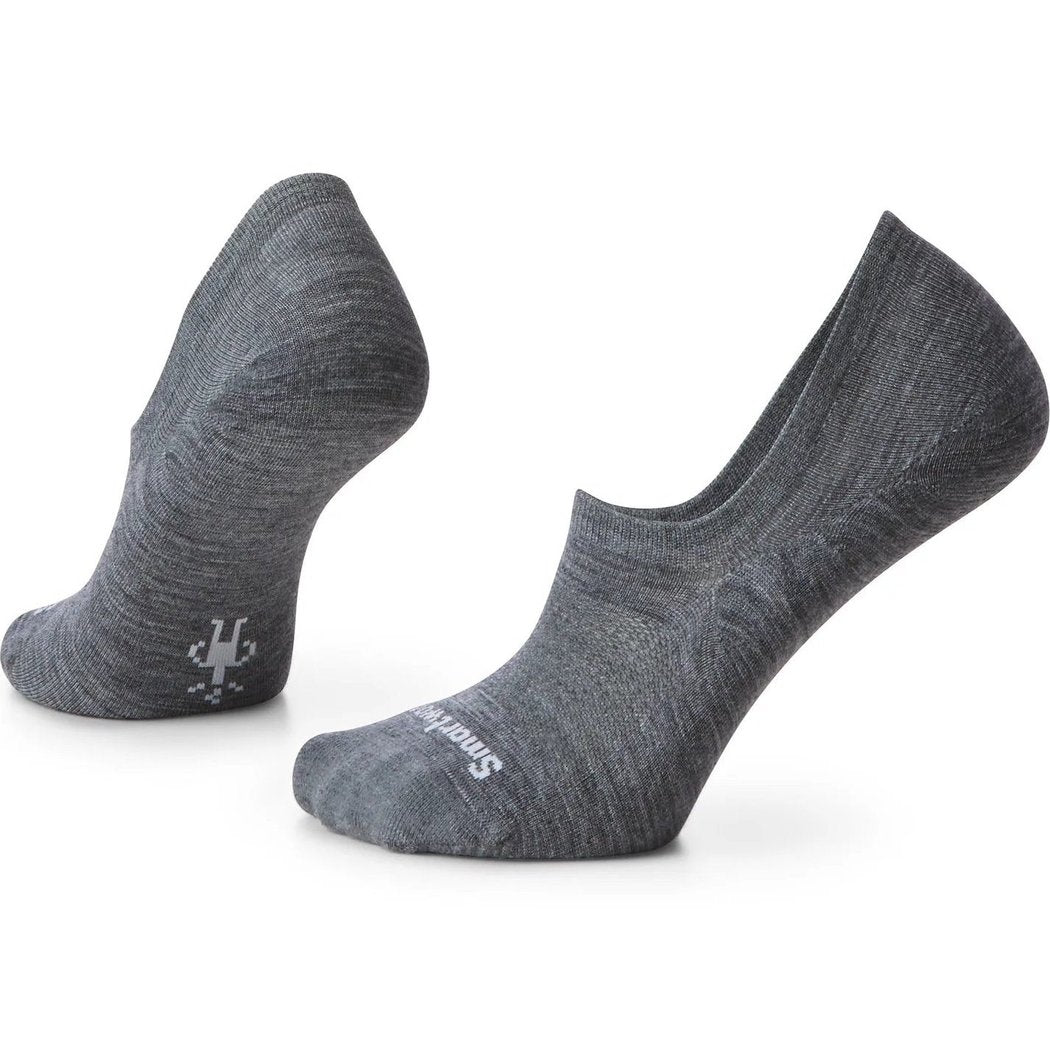 A woman sits cross-legged wearing Smartwool Everyday No Show Socks in Medium Gray with a white sneaker and blue jeans against a white background.