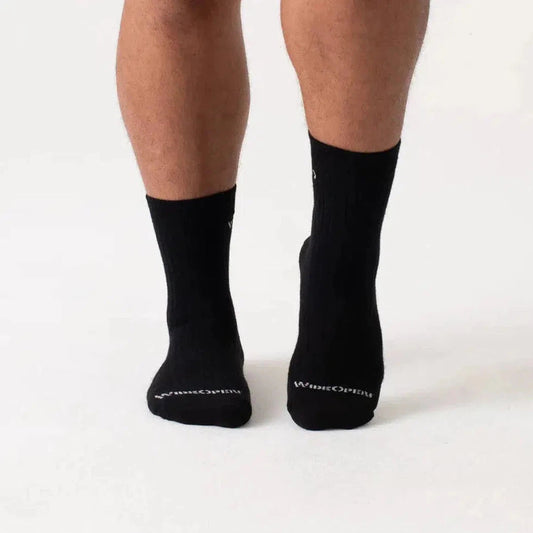 Back view of black Wide Open Men's Solid Cushioned Micro Crew Socks on a person against a white background.